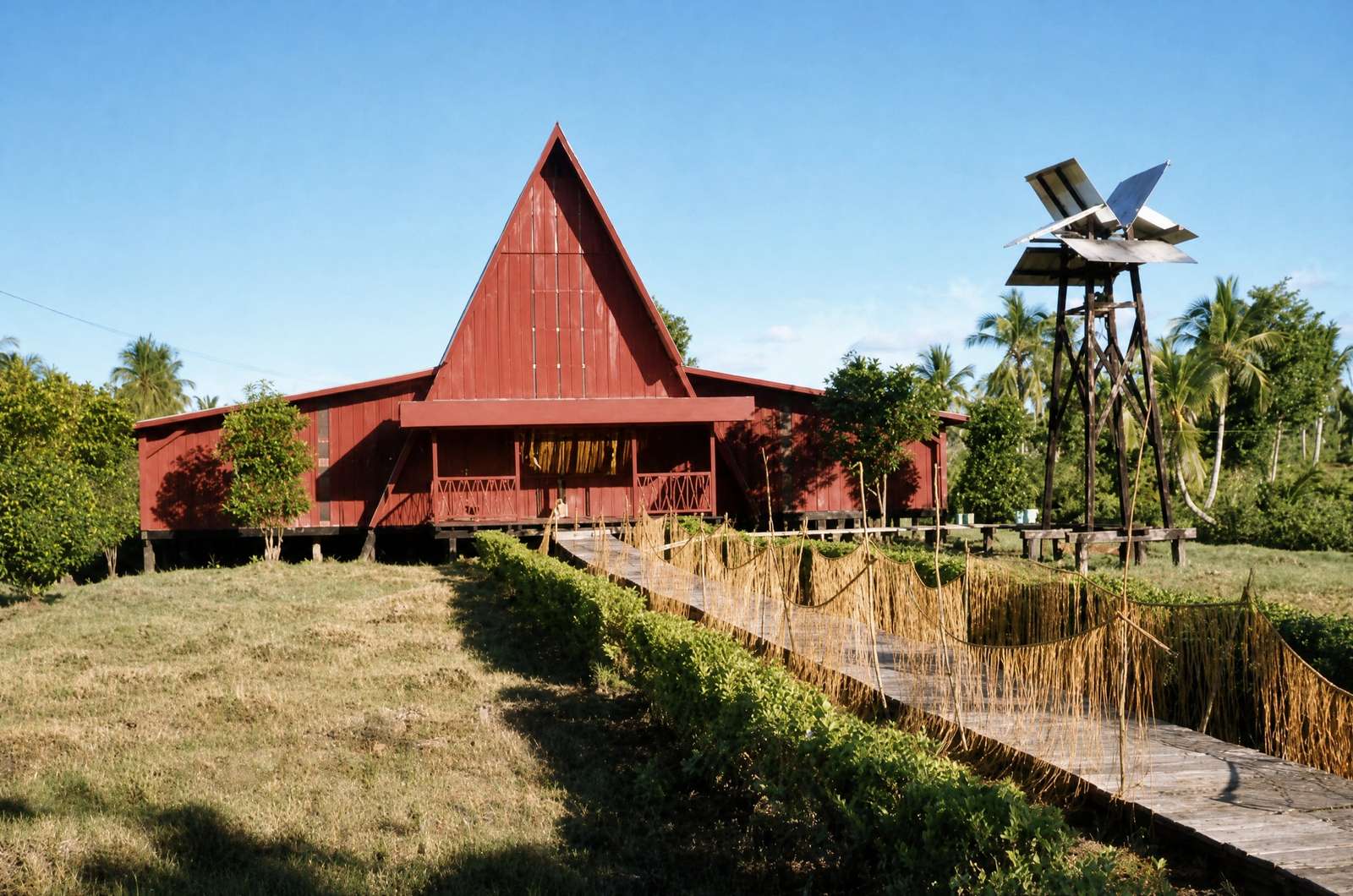 The cathedral when its timber was painted dark red, with the bell tower and a boardwalk through tall grass