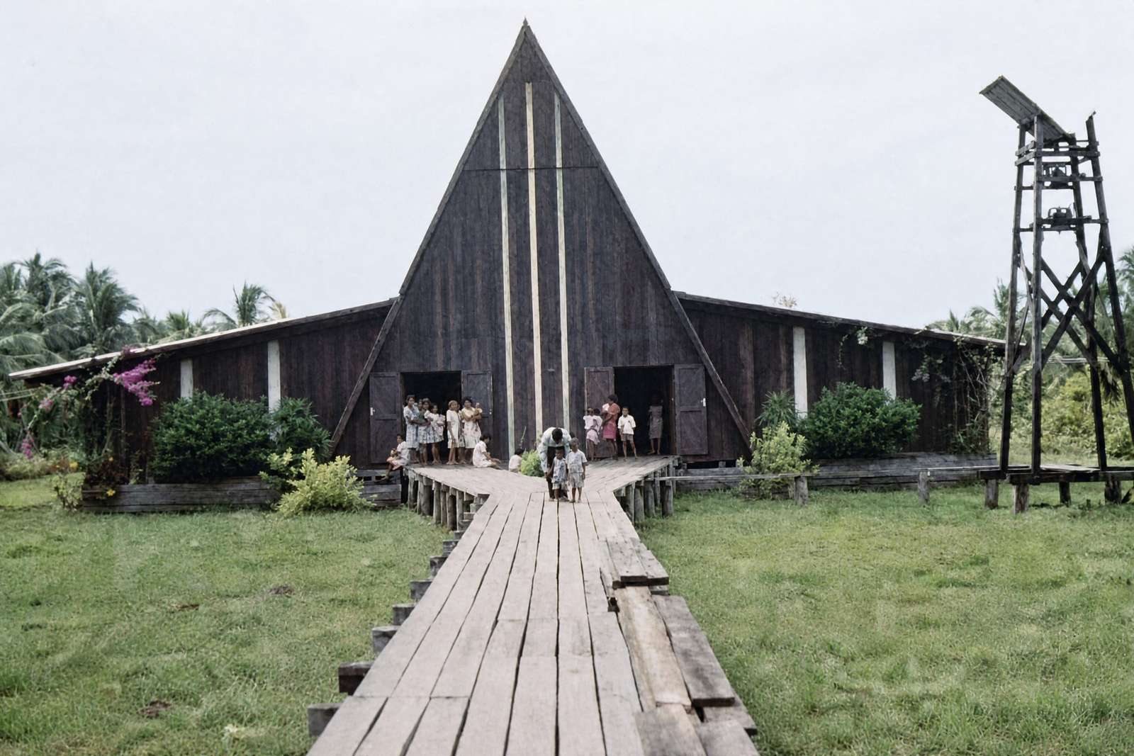 The present cathedral seen along the boardwalk, people at the door and the bell tower on the right