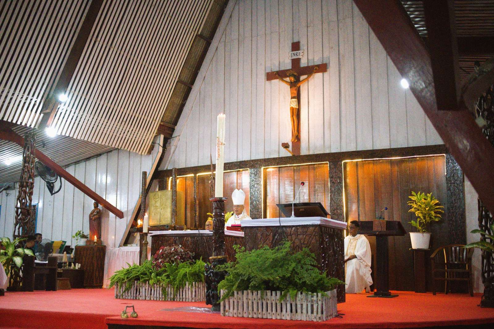 Mass in the present cathedral: the crucifix, candles, the carved altar and the priest at the ambo